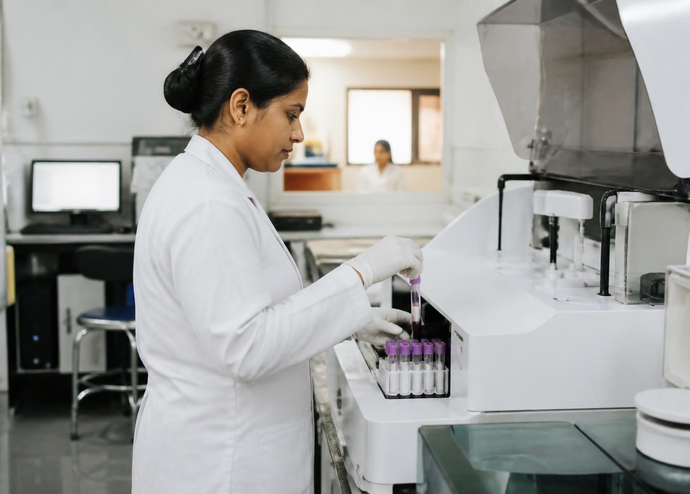 Laboratory technician processing blood samples on an automated analyser