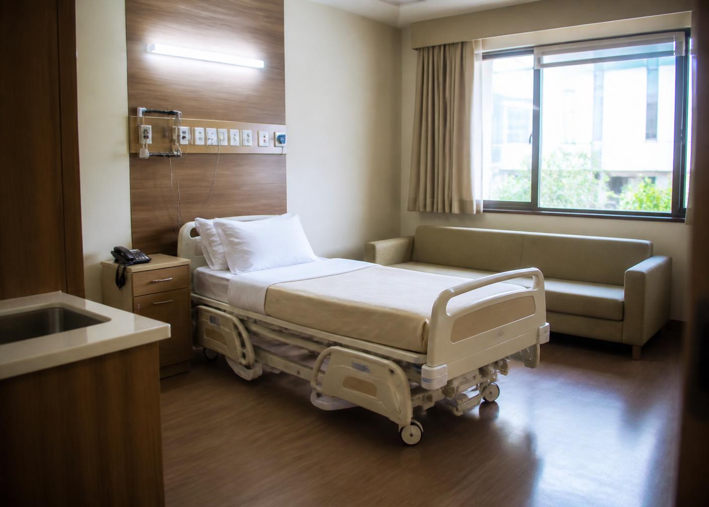 Private inpatient room with hospital bed and attendant seating